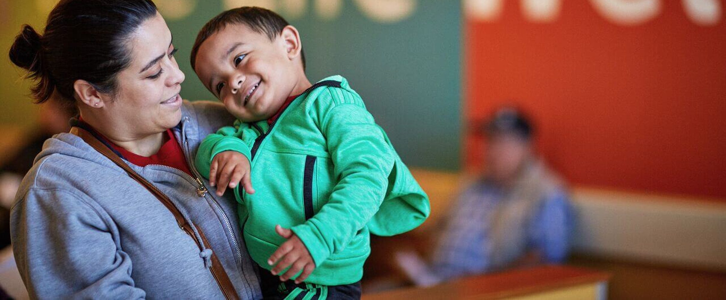 A mother holding her smiling young son at an Aliados Health member health center