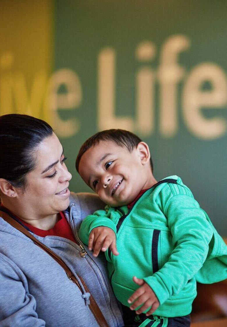 A mother holding her smiling young son at an Aliados Health member health center