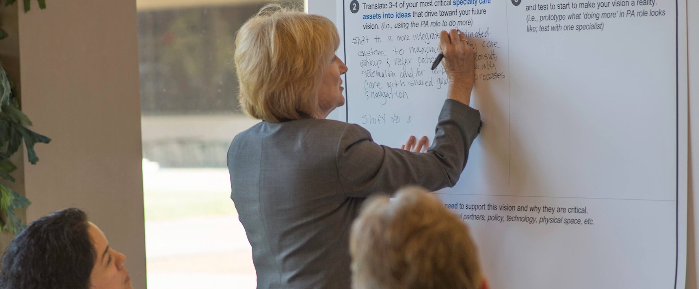 A health center leader writing on a whiteboard during a peer network session