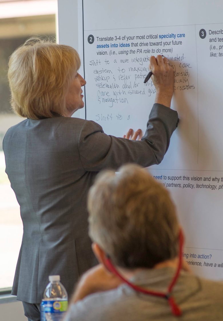A health center leader writing on a whiteboard during a peer network session